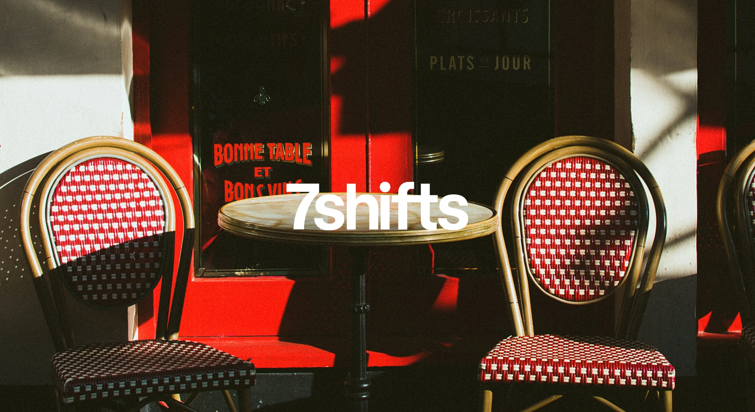 Two red chairs and a table in front of a restaurant.